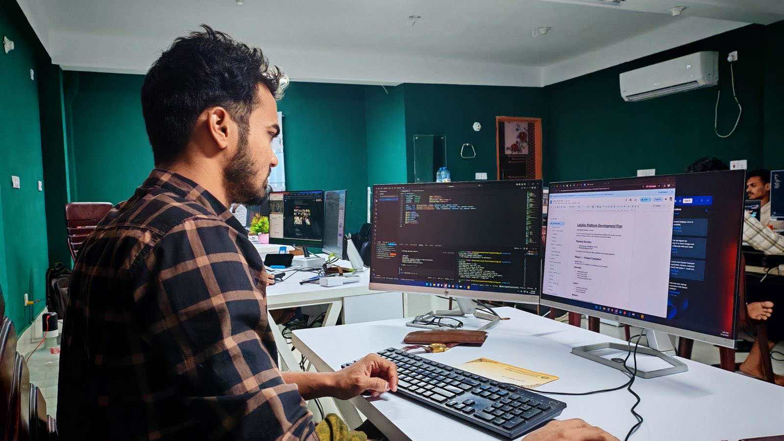 Developer comparing two files on dual monitors, like llms.txt and robots.txt